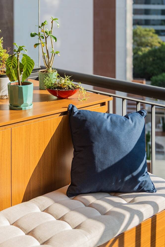 Aqui, a varanda ganhou um assento a mais e um espaço para o cultivo de plantas, que poderão receber muita luz natural no móvel que camufla a condensadora | Foto: Guilherme Pucci
