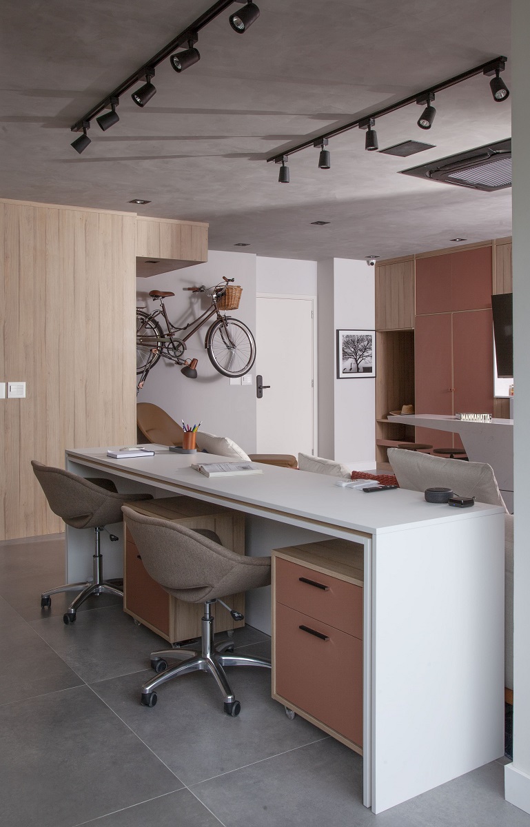 Aqui, o escritório fica em um lugar privativo, mas integrado ao estar. A mesa espaçosa (com 65 cm de profundidade e 2,8 m de extensão), dispõe de até três lugares. Enquanto os gaveteiros com rodinhas seguem de um lado para o outro rapidamente, as cadeiras têm ajuste de altura | Projeto BMA Studio | Foto: Luís Gomes